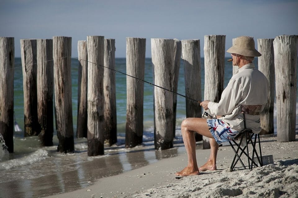 "Naples, USA - January 1, 2012: A picture of an old man fishing on the beach."